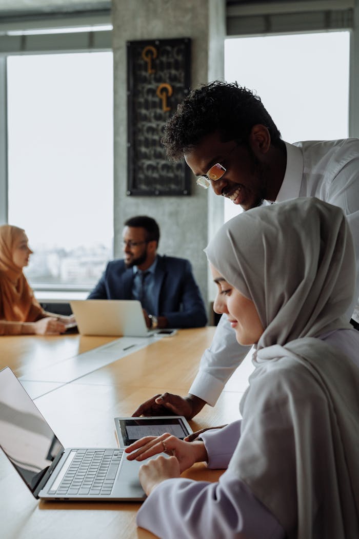A diverse team of professionals collaborating in a modern office setting with laptops.